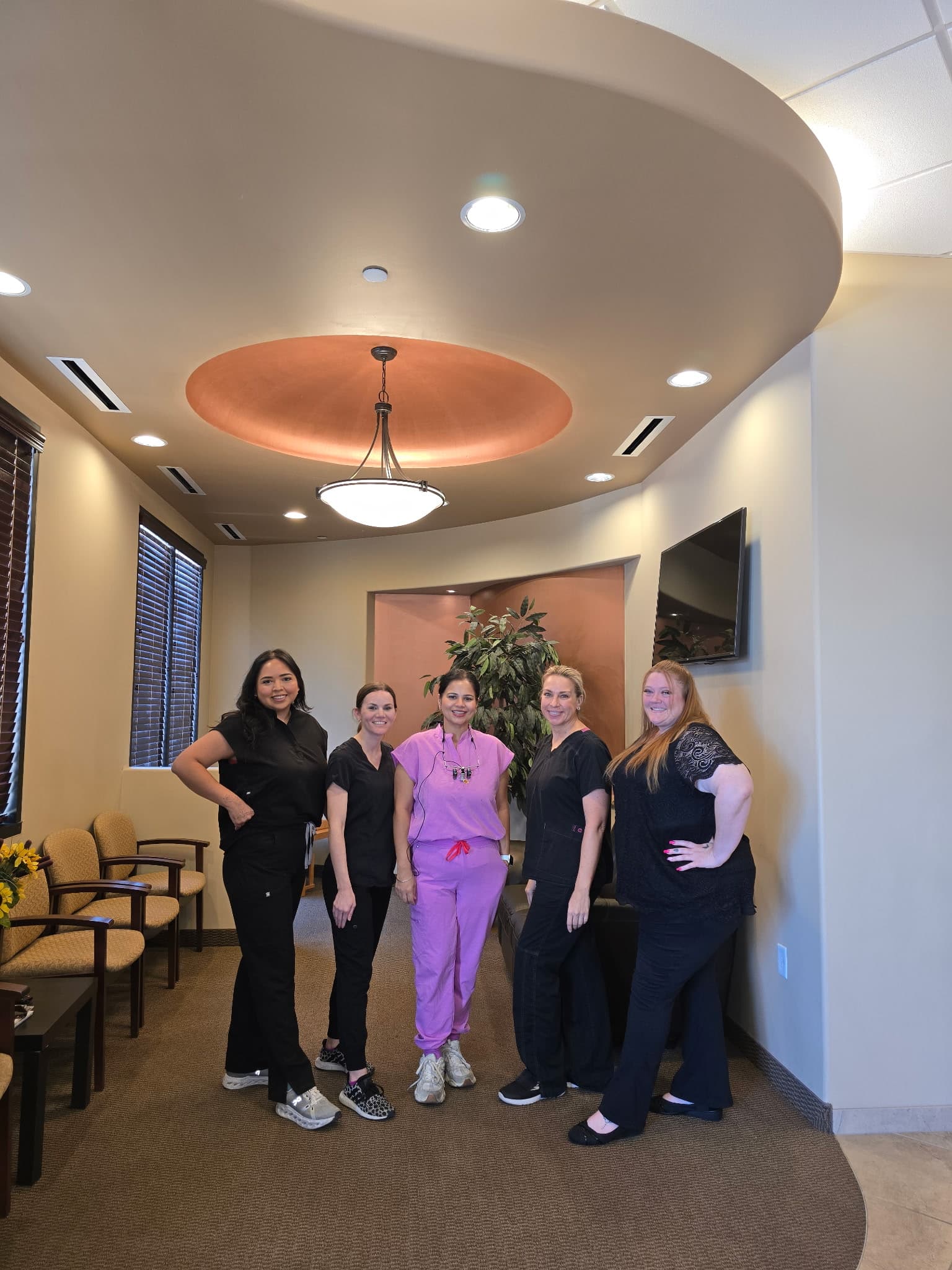 The five-person Promenade Dental team standing together in the practice's reception area in Chandler, Arizona.