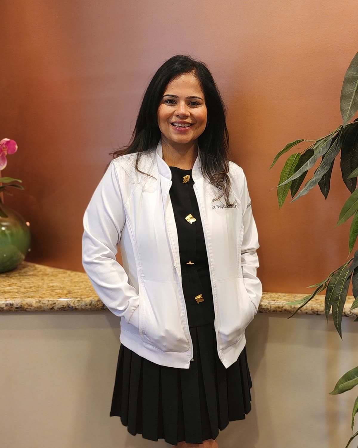 Dr. Shriya Sarin, DMD, smiling in a white coat inside Promenade Dental in Chandler, Arizona